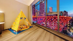 A room with a large window, a yellow tent, and a view of a cityscape at dusk. - Echarm Hotel JiefangbeiPedestrianStreet  (Chongqing)