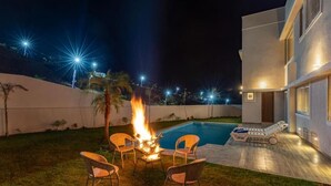 A backyard with a swimming pool, a fire pit, and outdoor furniture. - ELIVAAS Luxe Shourya Eden 3 BHK villa  (Udaipur)