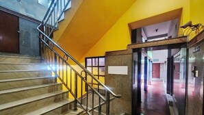 A staircase with metal railings leading to a landing with a glass door. - Hotel Sushil International (Kolkata)
