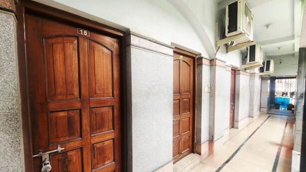 A hallway with wooden doors, numbered 18, and a tiled floor. - Hotel Sushil International (Kolkata)