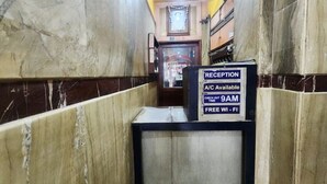 A reception area with a marble wall, a reception desk, and a sign indicating A/C availability, check-out time, and free Wi-Fi. - Hotel Sushil International (Kolkata)