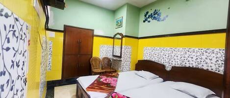 A bedroom with a bed, a ceiling fan, a wooden wardrobe, and a chair.