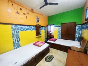 A room with two beds, a ceiling fan, a wooden wardrobe, and a chair. - Hotel Sushil International (Kolkata)