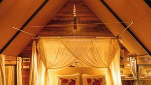 Een gezellige slaapkamer met een hemelbed, twee rode fauteuils en een klein rond tafeltje.
