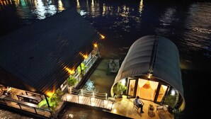 Een pand aan het water met een eethoek, een overdekt terras en een opvallende, bolvormige structuur met een glazen gevel.