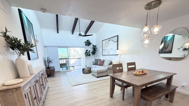 Ein geräumiger Wohnbereich mit einem Holzesstisch, einer Couch und einem großen Fenster, das für natürliches Licht sorgt.