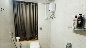 A small, tiled bathroom with a shower, toilet, and a hand dryer.