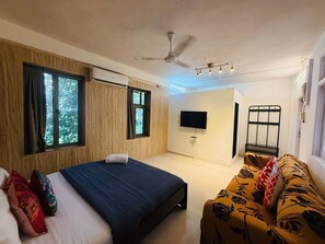 Un dormitorio con cama, sofá, televisor y ventilador de techo.