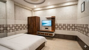 Un dormitori amb un llit, un televisor fixat a un moble de fusta i rajoles de paret amb motius.