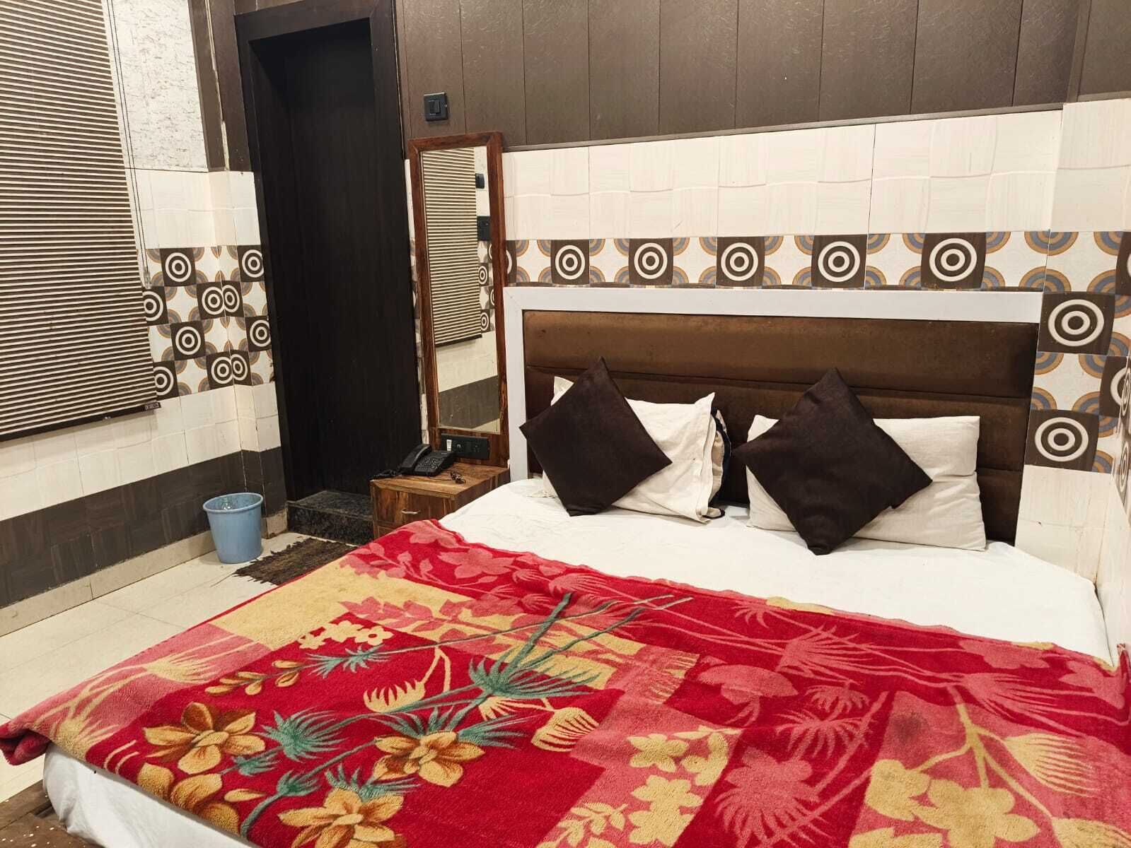 A hotel room with a bed, pillows, a bedside table, a telephone, and a blue bucket.