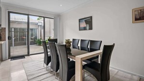 A modern dining area with a glass door leading to an outdoor space, a wooden table, and black chairs.