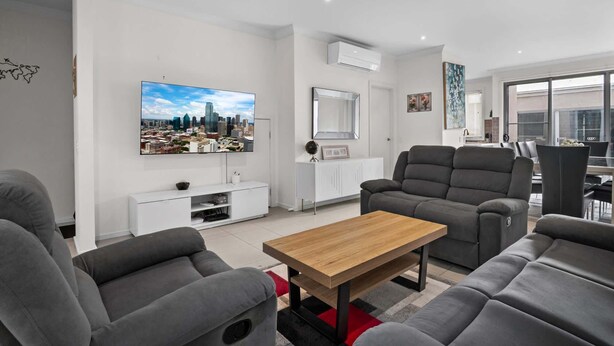 A modern living room with grey sofas, a wooden coffee table, a flat-screen TV, and a white entertainment unit.