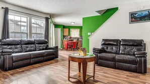 A living room with two black leather sofas, a wooden coffee table, and a green accent wall. - Patio & Yard! Family Home, 6 Mi to Airport (Indianapolis)