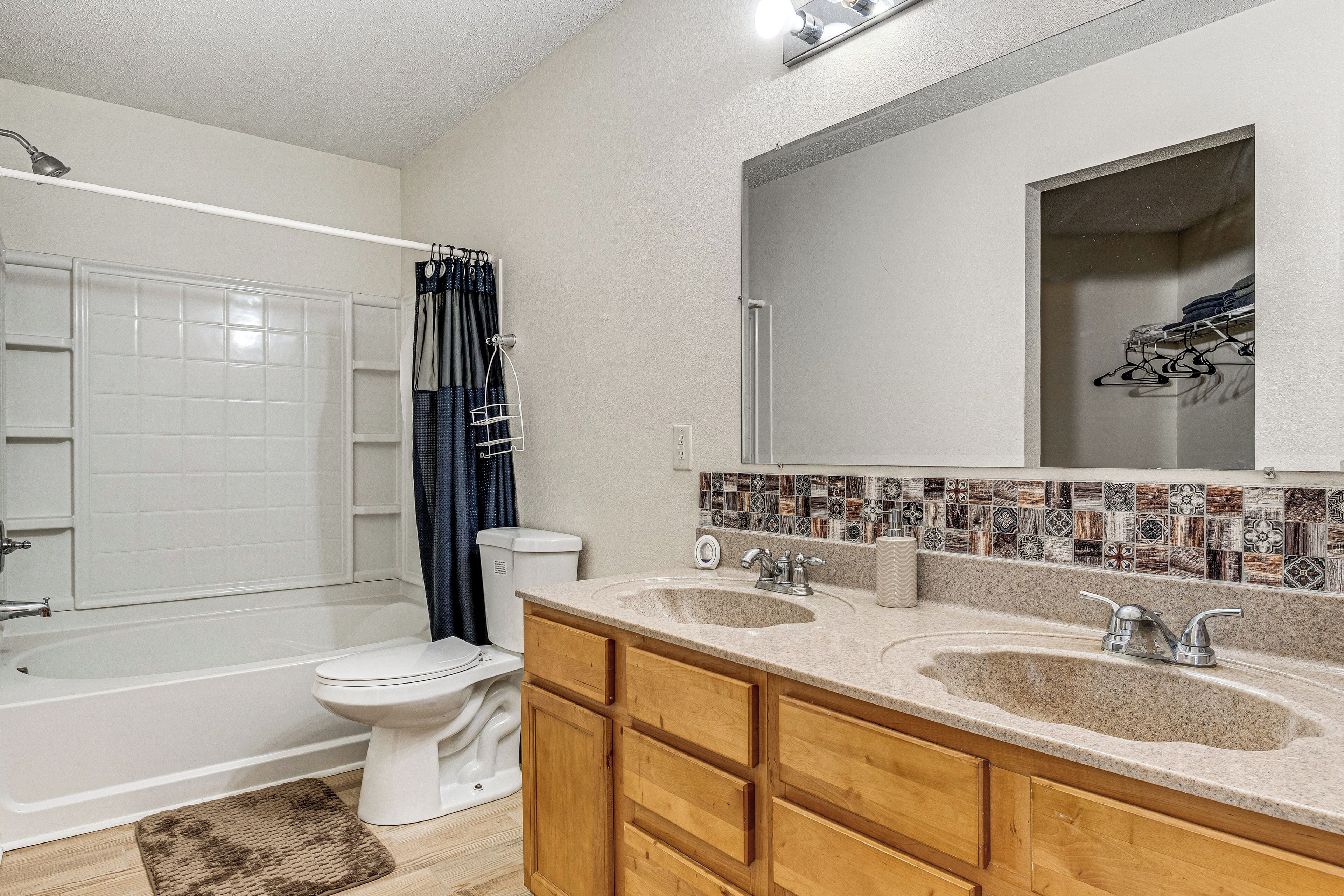 A bathroom with a bathtub, toilet, and double sink vanity.