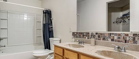 A bathroom with a bathtub, toilet, and double sink vanity.