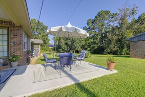 A patio with a table and chairs, an umbrella, and a potted plant. - Noxapater Fall Retreat for Hunting & MSU Games (Noxapater)
