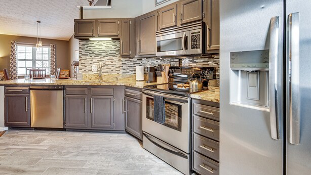 A modern kitchen with stainless steel appliances, a herringbone tile backsplash, and a built-in oven. - Castlerea Casa Columbus Home w/ Deck & Yard (Columbus)