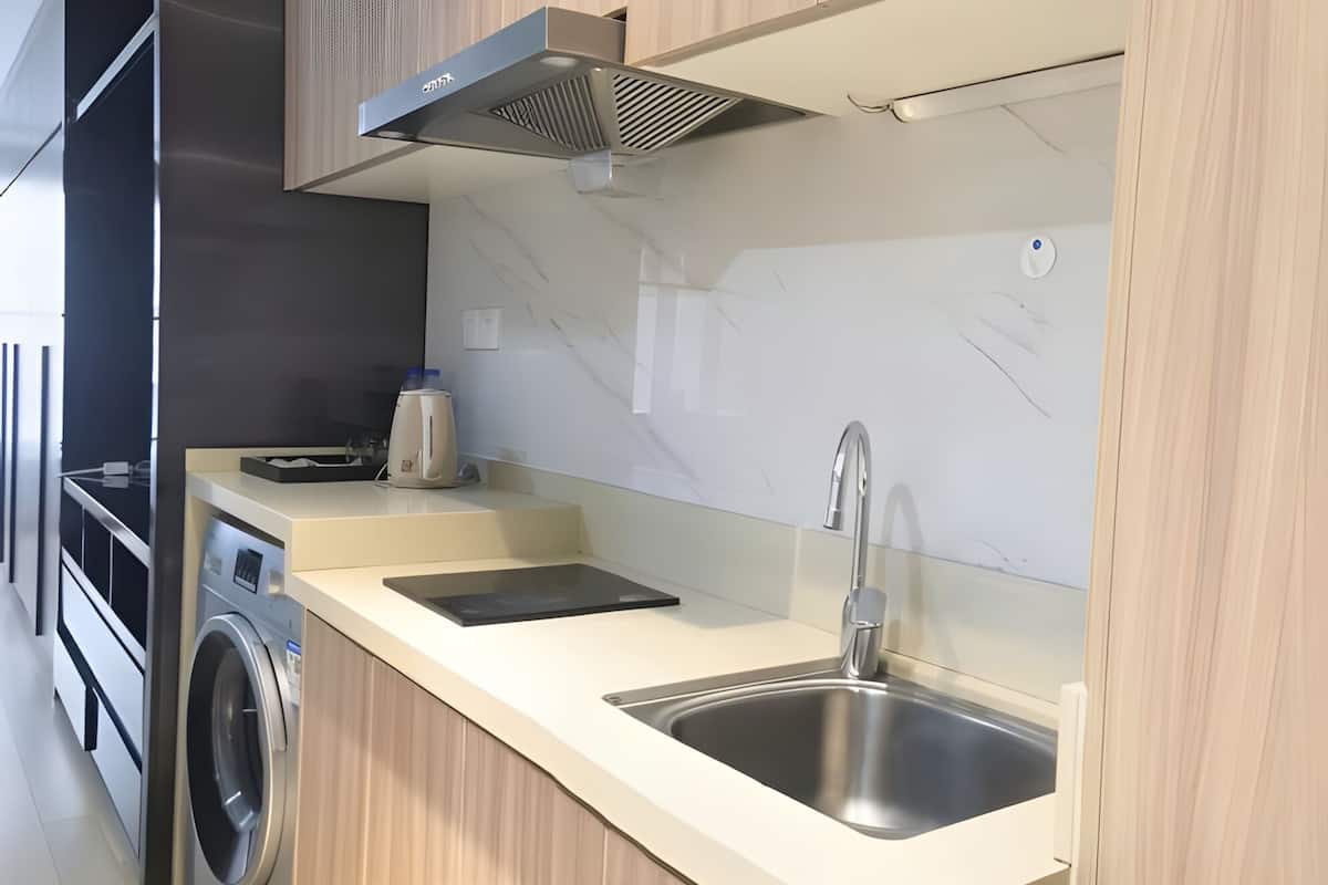 Una cocina moderna con lavadora integrada, un lavamanos de acero inoxidable y una campana extractora.