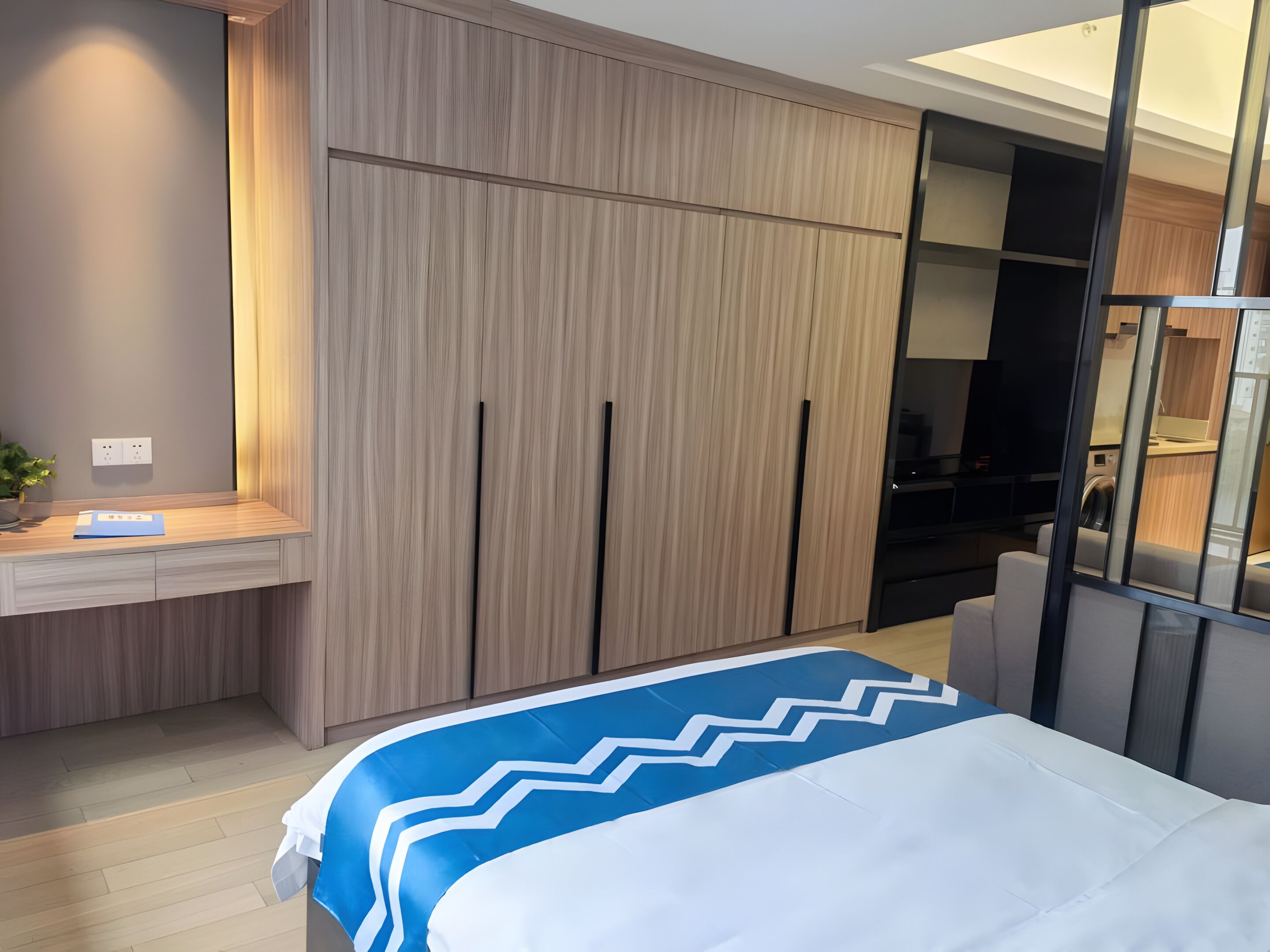 A modern bedroom with a bed, a desk, and a wardrobe.