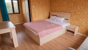 Une chambre à coucher avec un lit en bois, une table de chevet, une chaise et une fenêtre avec des rideaux.