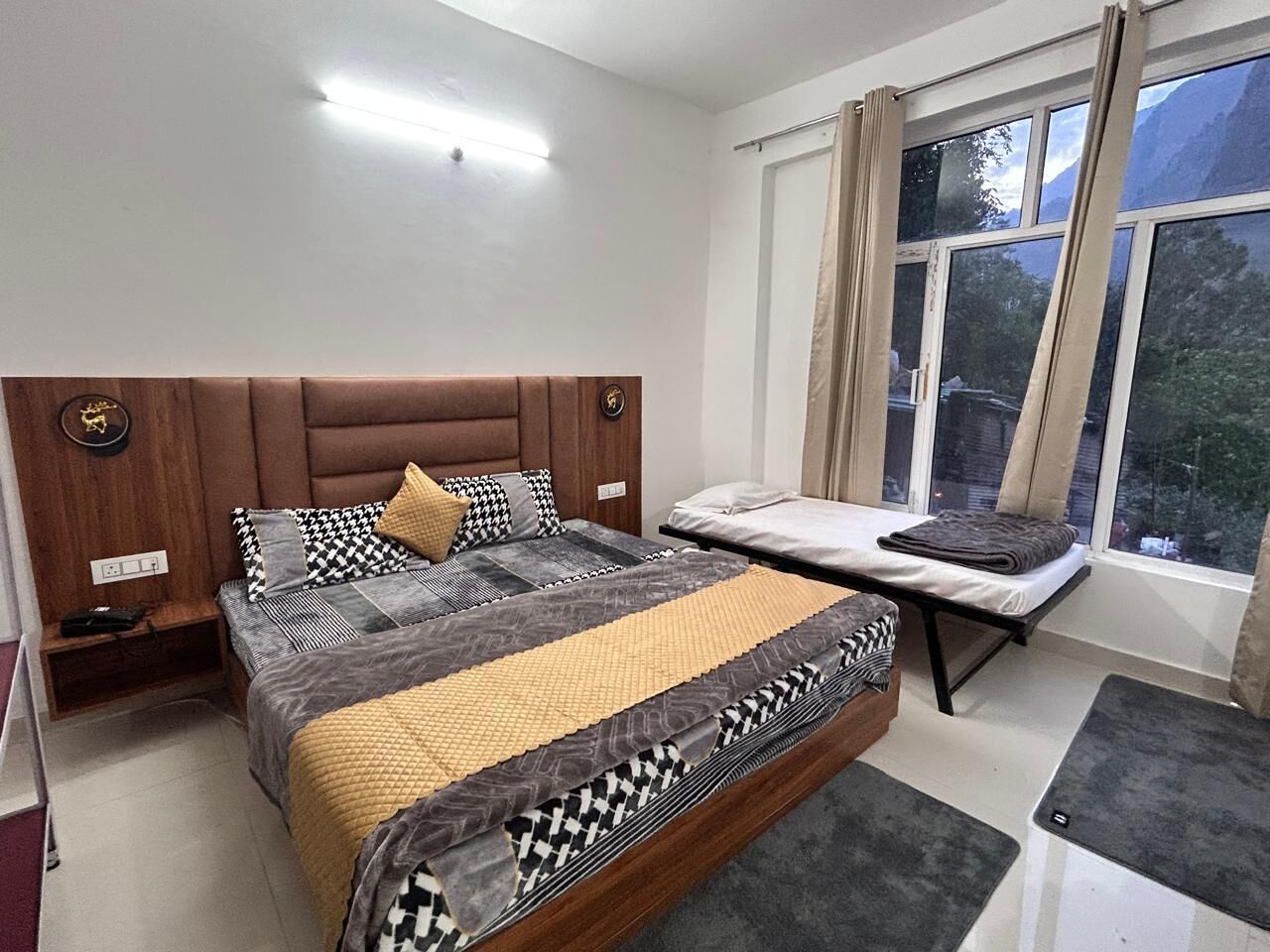Une chambre à coucher avec un lit, des tables de chevet, un banc et une fenêtre avec des rideaux.