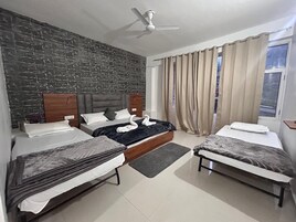 A hotel room with a brick wall, two beds, a ceiling fan, and a window with curtains.