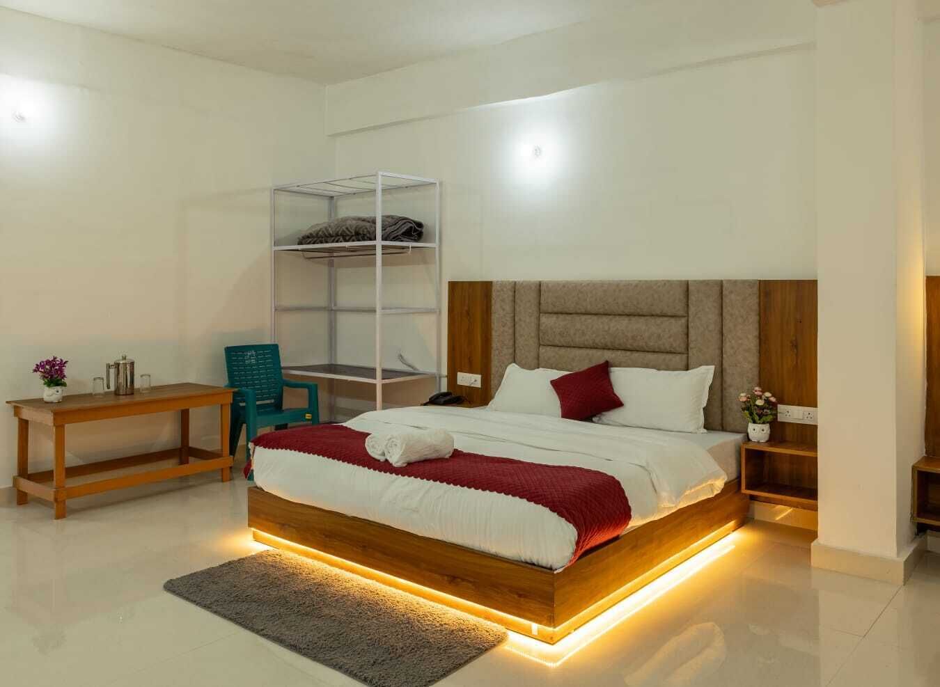 Un dormitorio moderno con una cama de madera, una mesita de noche, una silla, una estantería y un escritorio.