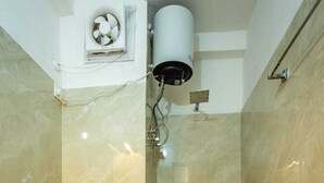 A bathroom with a toilet, shower, and a water heater. - Hotel Gurudeva  (Joshimath)