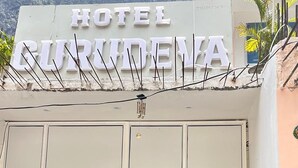 A group of people standing in front of a hotel entrance with a sign that reads 'HOTEL GURUMEVA.' - Hotel Gurudeva  (Joshimath)