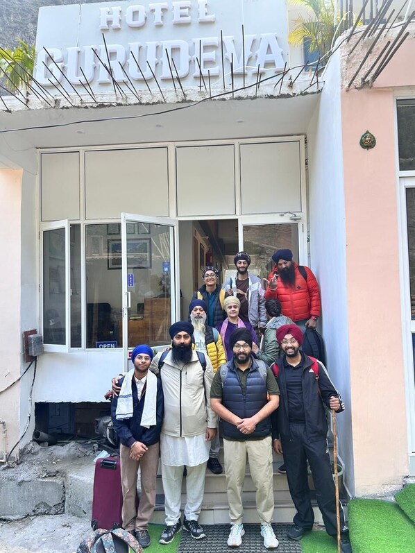 A group of people standing in front of a building with a sign that reads 'HOTEL'. - Hotel Gurudeva  (Joshimath)