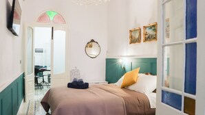 A hotel room with a bed, a mirror, and a door leading to a dining area. - Traditional Maisonette - Yard & Jacuzzi (Mgarr)