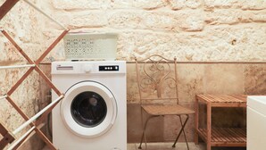 A compact laundry area with a washing machine, a drying rack, and a small wooden table. - Traditional Maisonette - Yard & Jacuzzi (Mgarr)