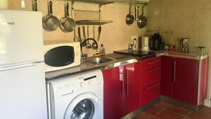 A compact kitchen with a washing machine, microwave, sink, and red cabinets. - Gîte les Coquelicots facing the river (Vignonet)