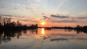 A calm lake reflecting the sunset with silhouettes of trees and a clear sky. - Gîte les Coquelicots facing the river (Vignonet)