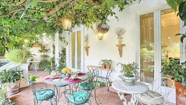 A covered patio area with tables and chairs, surrounded by potted plants and hanging baskets. - Villa Astarte: An elegant apartment located in the center of Sorrento, with Free WI-FI. (Sorrento)