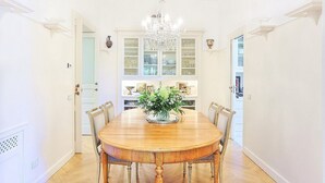 A dining room with a wooden table, chairs, a chandelier, and a cabinet with glass doors. - Villa Astarte: An elegant apartment located in the center of Sorrento, with Free WI-FI. (Sorrento)