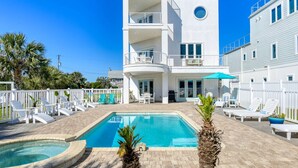 Un edificio de dos pisos con piscina, mobiliario exterior y valla blanca.