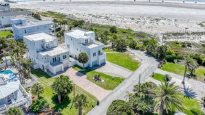 Una propiedad costera con varios edificios blancos, una piscina y vista a la playa y al océano.