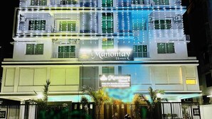 A multi-story building with illuminated signage for Manomay Homes, featuring a modern architectural design with multiple balconies and large windows. - hotel manomay homes (Nagpur)