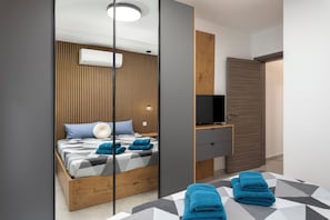 A modern bedroom with a bed, a TV, and a wooden wardrobe. - Modern Stylish 2BR APT With 2 Balconies (San Ġwann)