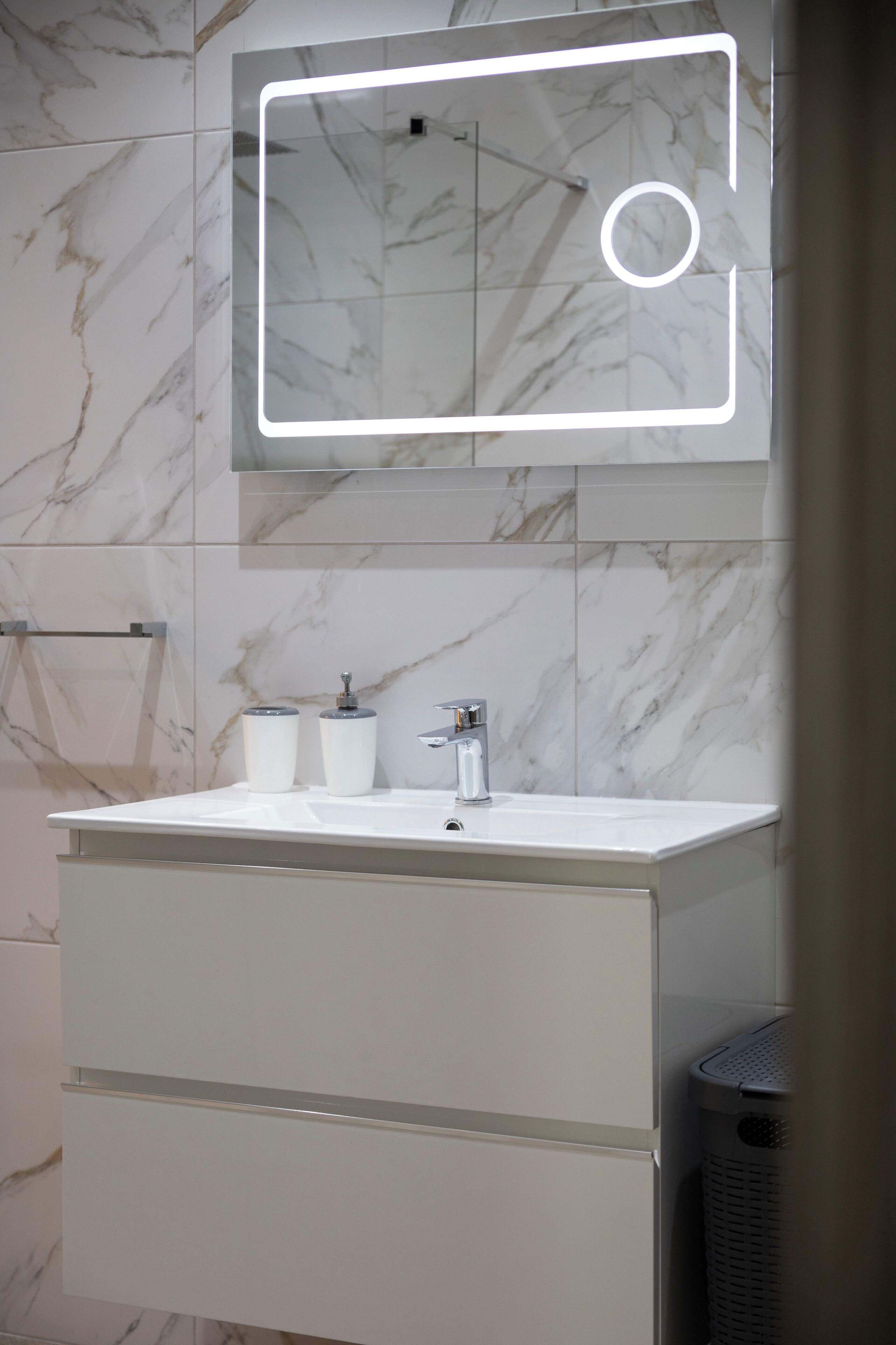 Une salle de bain avec un lavabo en marbre blanc, un miroir et une poubelle.