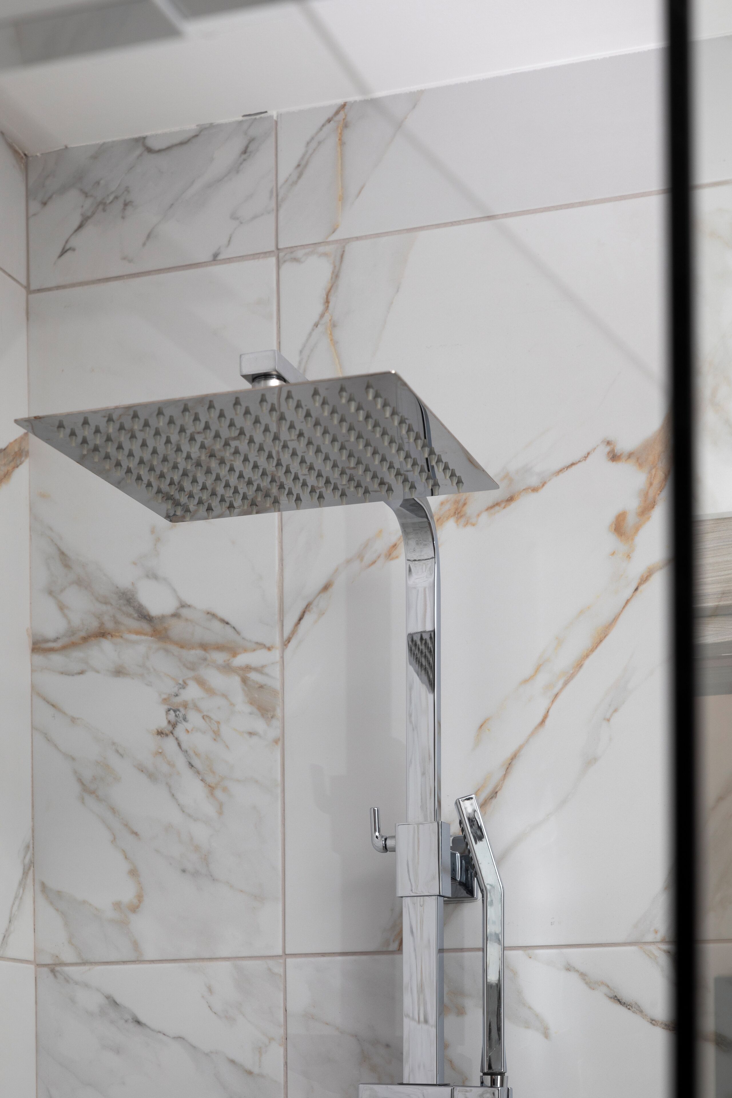 Eine Dusche mit modernem, eckigem Design und Chromoberfläche.