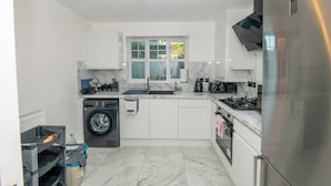 Een kleine keuken met een wasmachine, een spoelbak, een kookplaat en een koelkast.