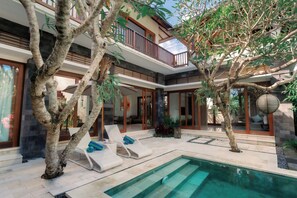 Ein modernes Haus mit Pool, Liegestühlen und einem Balkon.