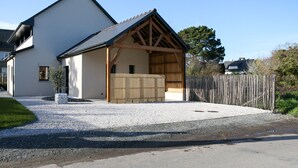 A modern house with a gravel driveway and a wooden fence. - Ker Lou (Cancale)