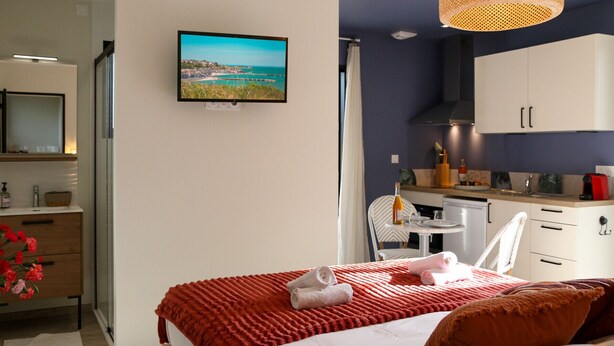 A bedroom with a bed, a TV, a kitchenette, and a bathroom. - Ker Lou (Cancale)