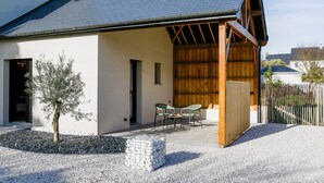 A modern house with a covered patio, a small tree, and a gravel driveway. - Ker Lou (Cancale)