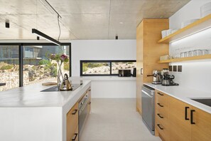 A modern kitchen with a large island, built-in appliances, and a view of a rocky landscape.