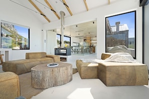 A modern living room with a large window, a round wooden coffee table, and a sofa. - Nowhere Els (Rooiels)