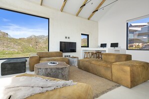 A modern living room with a large window, a sofa set, a coffee table, and a flat-screen TV.